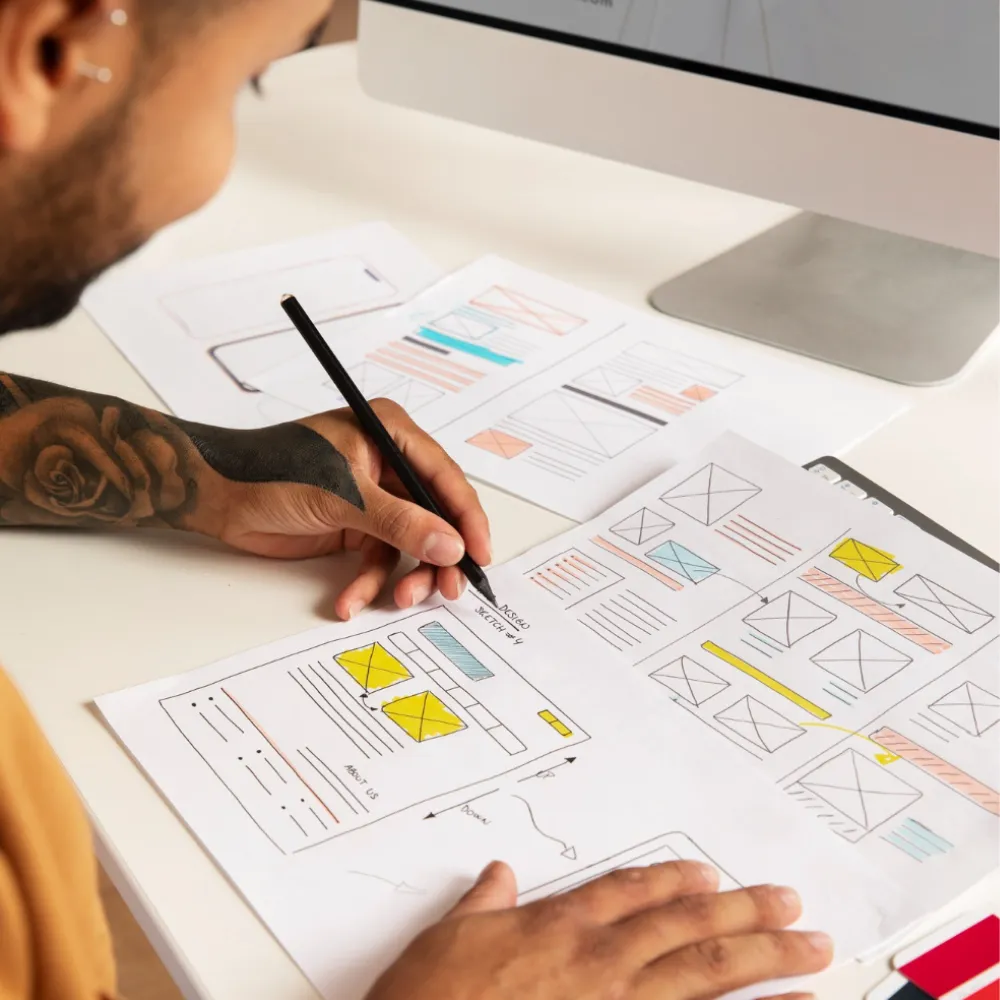 Web designer sketching user-centric website wireframes by hand at a desk